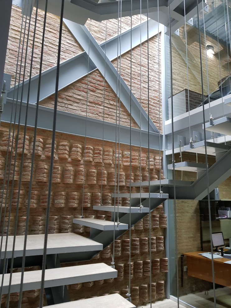 На фото: большая лестница на больцах в современном стиле с бетонными ступенями и кирпичными стенами без подступенок
