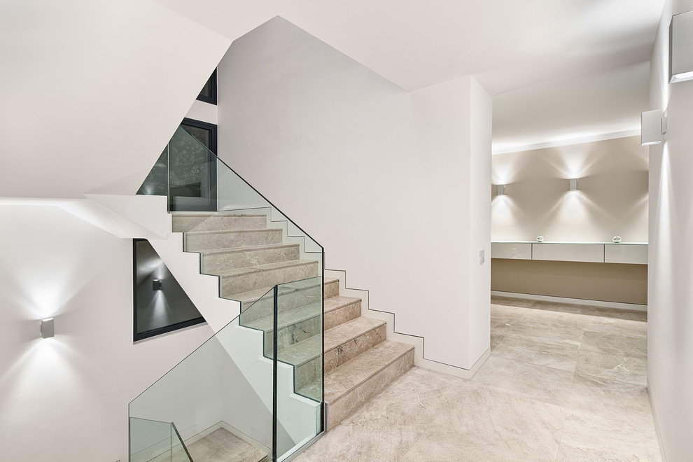Modelo de escalera en U moderna grande con escalones de piedra caliza, contrahuellas de piedra caliza y barandilla de vidrio