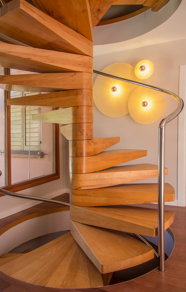 Ejemplo de escalera de caracol moderna grande con escalones de madera y barandilla de metal