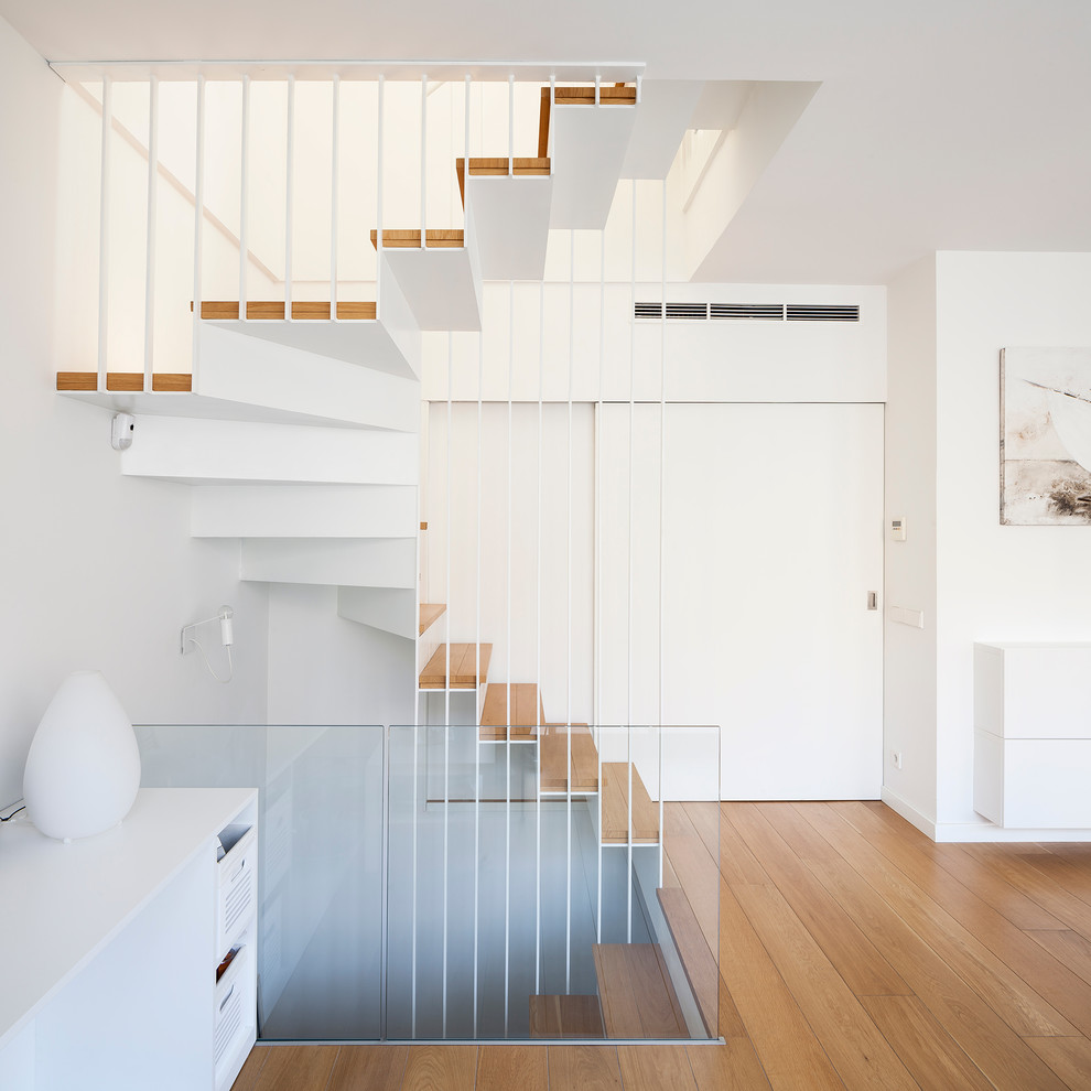 This is an example of a large scandinavian wood u-shaped staircase in Barcelona with metal risers and feature lighting.