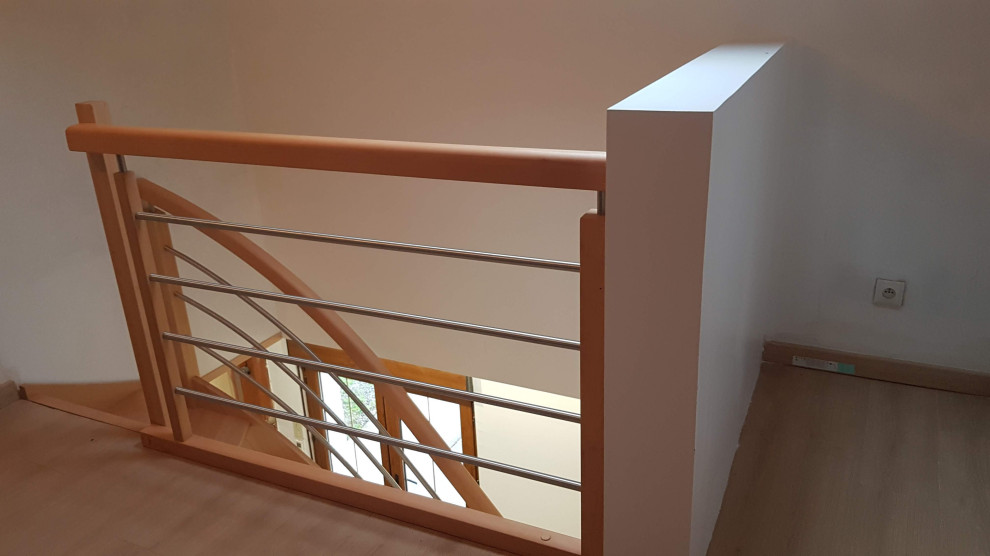 Aménagement d'un escalier courbe contemporain de taille moyenne avec des marches en bois et un garde-corps en métal.