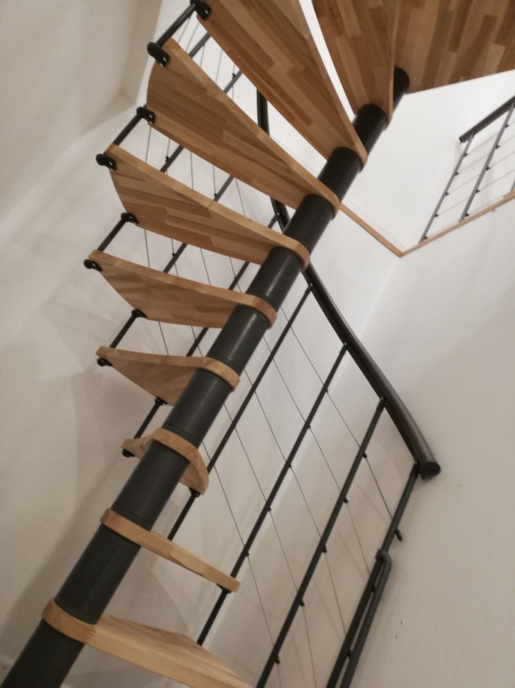 Cette photo montre un petit escalier hélicoïdal tendance avec des marches en bois et un garde-corps en câble.