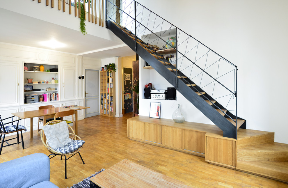 На фото: прямая лестница в скандинавском стиле с деревянными ступенями, металлическими перилами и кладовкой или шкафом под ней без подступенок
