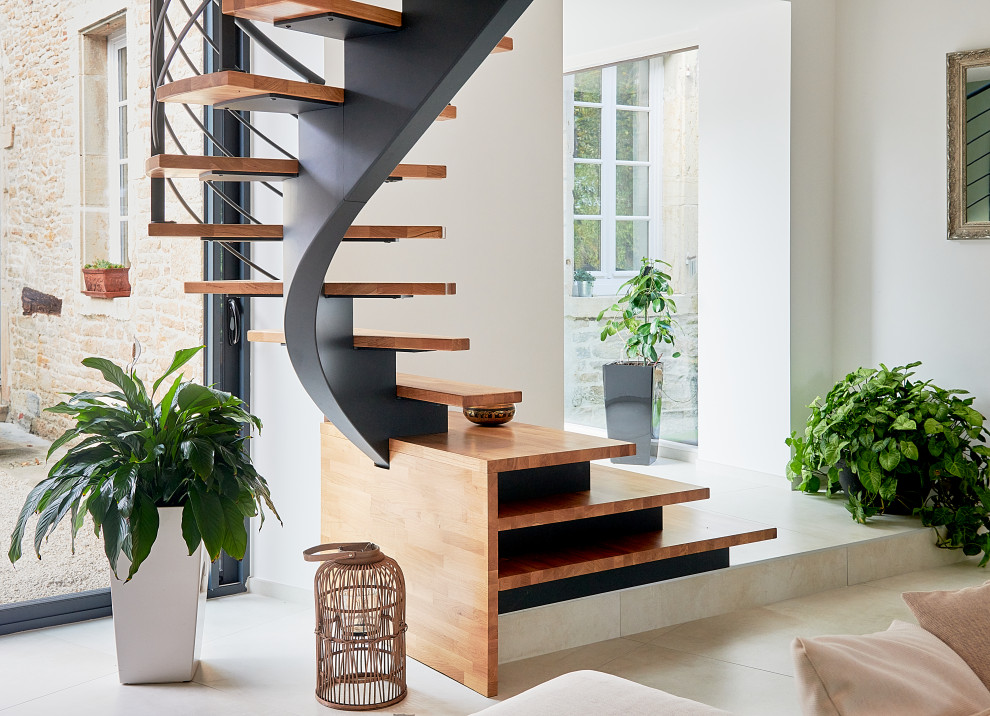 Cette photo montre un escalier courbe tendance de taille moyenne avec des marches en bois et un garde-corps en métal.