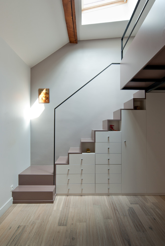 На фото: угловая лестница среднего размера в современном стиле с крашенными деревянными ступенями и кладовкой или шкафом под ней