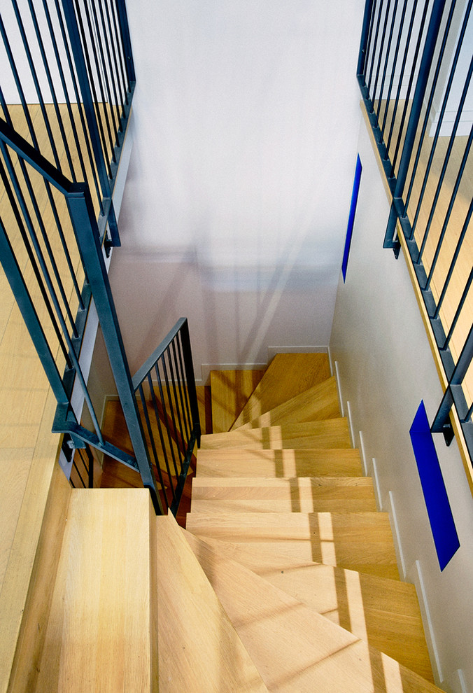 Idée de décoration pour un escalier courbe design de taille moyenne avec des marches en bois et des contremarches en bois.