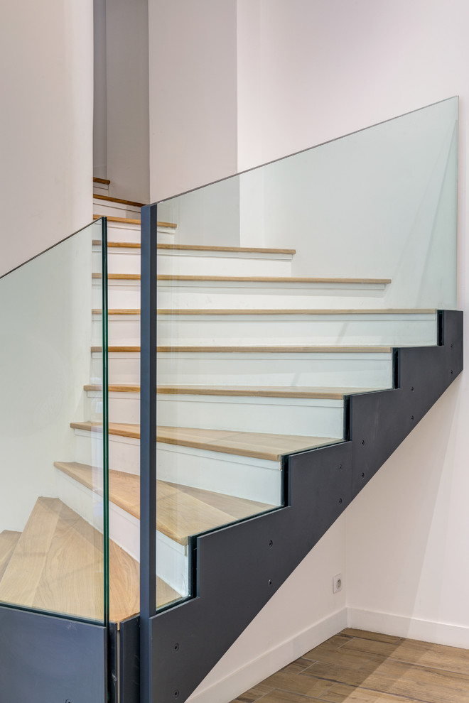 Cette photo montre un escalier peint courbe scandinave de taille moyenne avec des marches en bois et un garde-corps en verre.