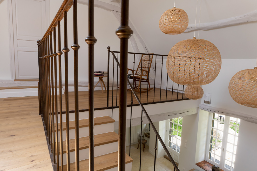На фото: большая угловая лестница в стиле фьюжн с деревянными ступенями и металлическими перилами с
