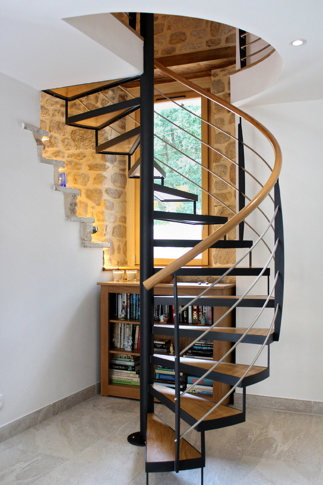 Ejemplo de escalera de caracol de estilo de casa de campo sin contrahuella con escalones de madera y barandilla de varios materiales