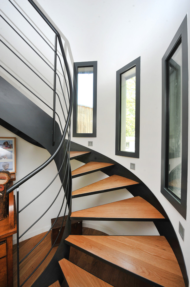 Idée de décoration pour un grand escalier sans contremarche courbe design avec des marches en bois.