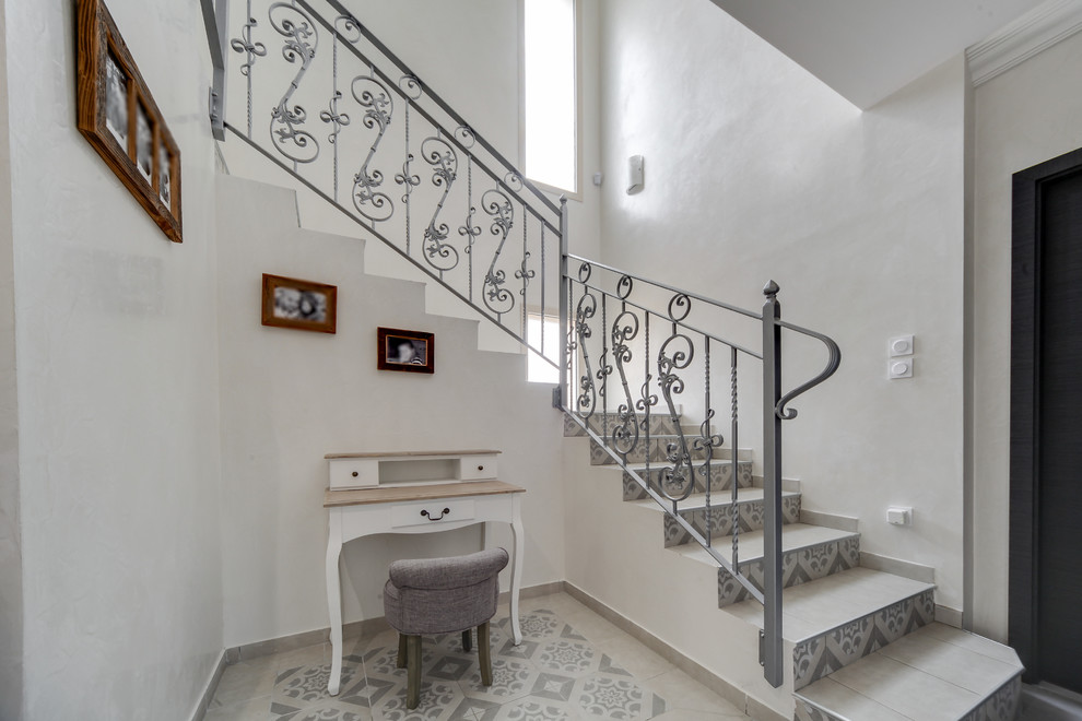 Foto de escalera curva moderna de tamaño medio con escalones con baldosas, contrahuellas con baldosas y/o azulejos y barandilla de metal