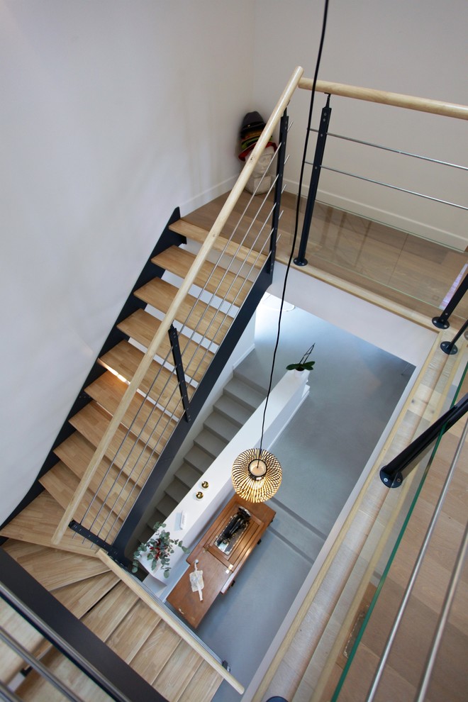 Aménagement d'un grand escalier hélicoïdal contemporain avec des marches en bois, des contremarches en bois et un garde-corps en bois.