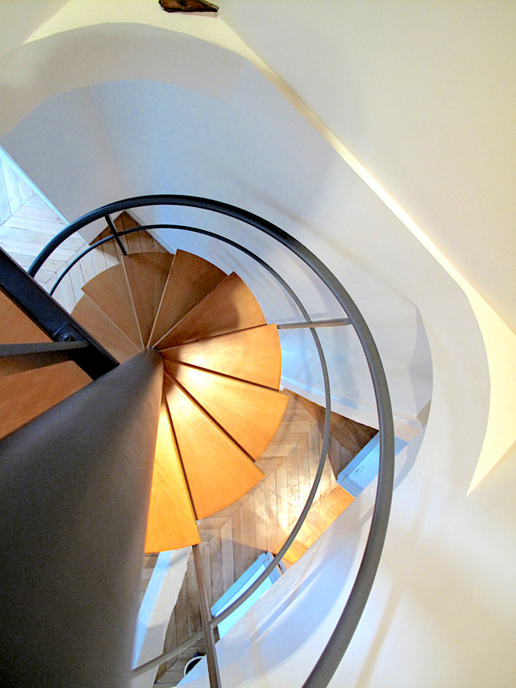 Inspiration for a small eclectic wood curved metal railing staircase in Paris with open risers.