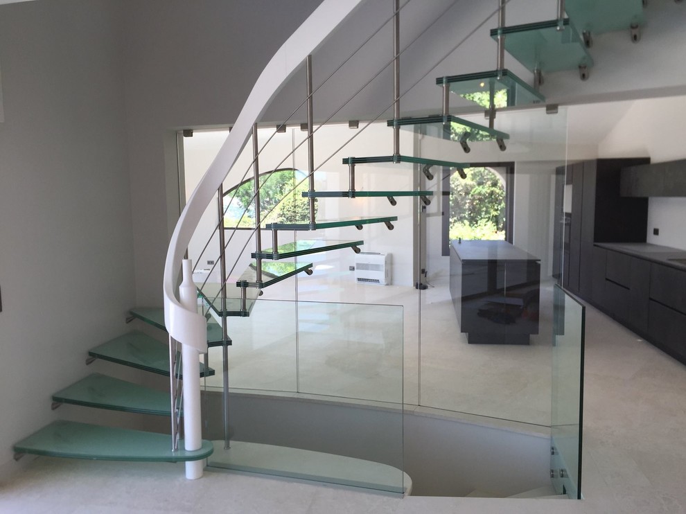 Exemple d'un grand escalier sans contremarche courbe tendance avec des marches en verre.