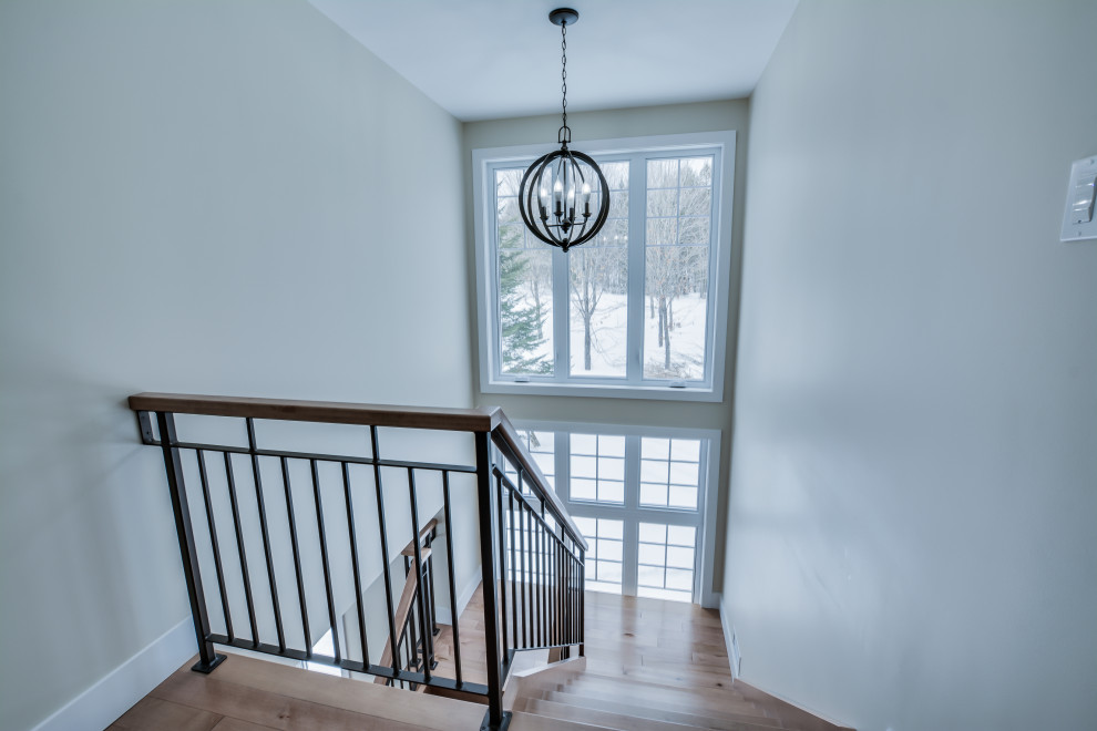 Imagen de escalera en U de estilo de casa de campo grande sin contrahuella con escalones de madera y barandilla de metal