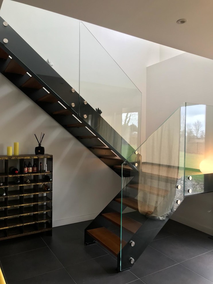 Ejemplo de escalera curva minimalista grande con escalones de madera pintada, contrahuellas de madera pintada y barandilla de vidrio