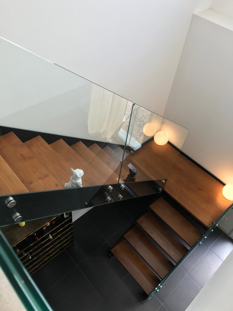 Large modern painted wood curved glass railing staircase in Lille with painted wood risers.