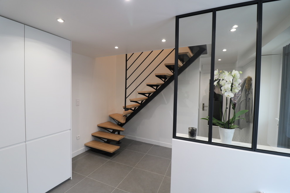 Réalisation d'un escalier courbe design de taille moyenne avec des marches en bois, des contremarches en bois et un garde-corps en métal.
