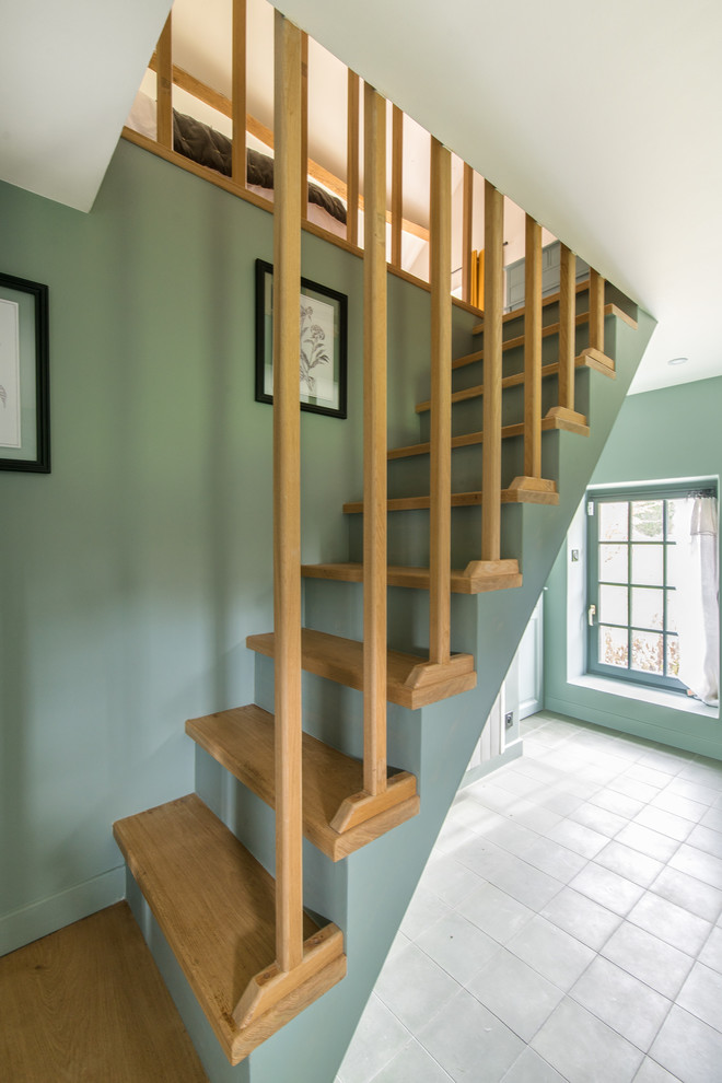 Medium sized country wood straight staircase in Other with painted wood risers.