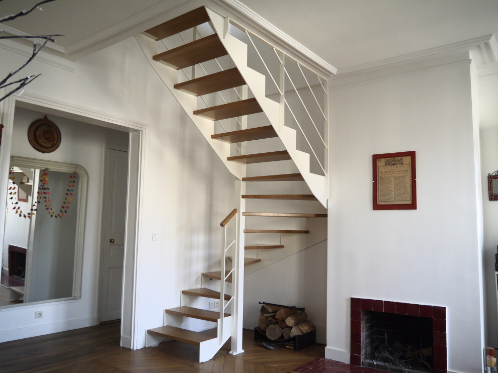 Exemple d'un escalier hélicoïdal tendance de taille moyenne avec des marches en bois et un garde-corps en métal.