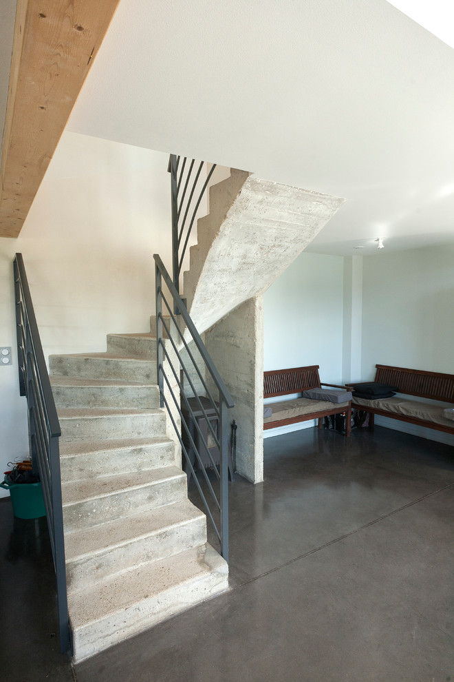 На фото: изогнутая бетонная лестница среднего размера в стиле лофт с бетонными ступенями