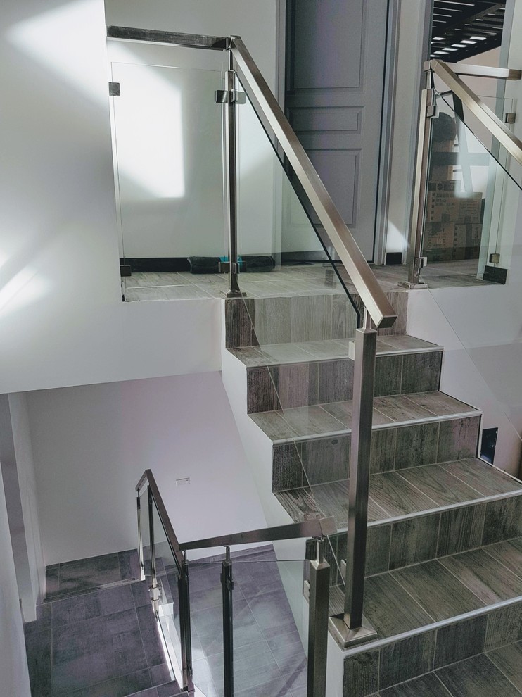 Пример оригинального дизайна: лестница на больцах, среднего размера в стиле модернизм с ступенями из плитки, подступенками из плитки и металлическими перилами