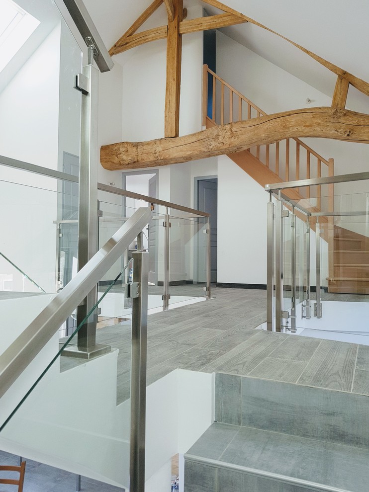 Ejemplo de escalera suspendida moderna de tamaño medio con escalones con baldosas, contrahuellas con baldosas y/o azulejos y barandilla de metal
