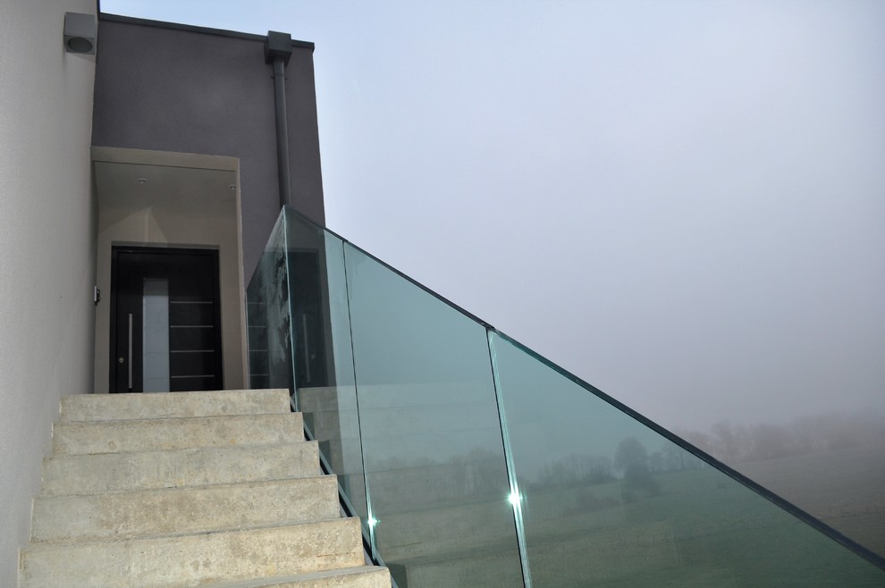 Modelo de escalera recta contemporánea grande con escalones de hormigón, contrahuellas de hormigón y barandilla de vidrio