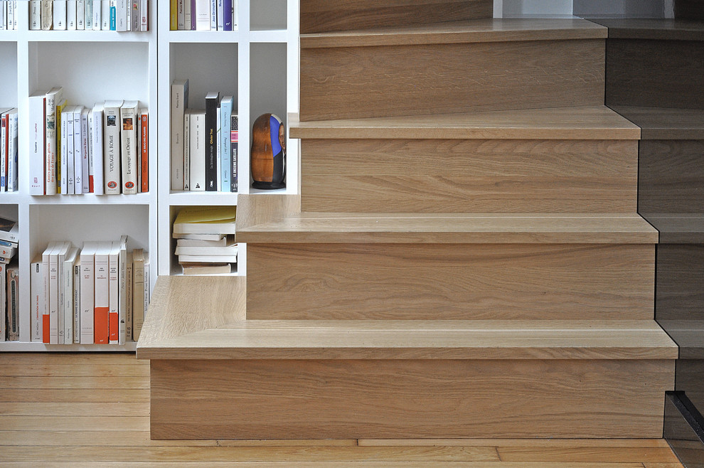 Idée de décoration pour un petit escalier courbe design avec des marches en bois, des contremarches en bois et un garde-corps en métal.