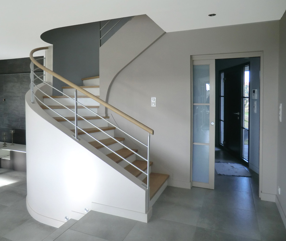 Large modern wood curved mixed railing staircase in Le Havre with concrete risers.