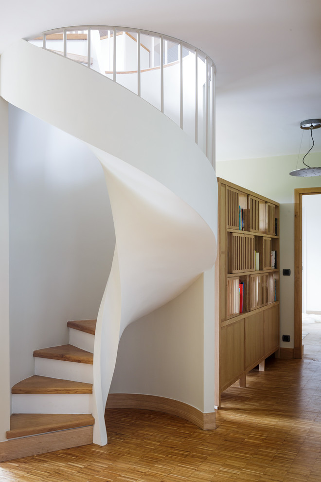 На фото: винтовая лестница среднего размера в современном стиле с деревянными ступенями и крашенными деревянными подступенками с