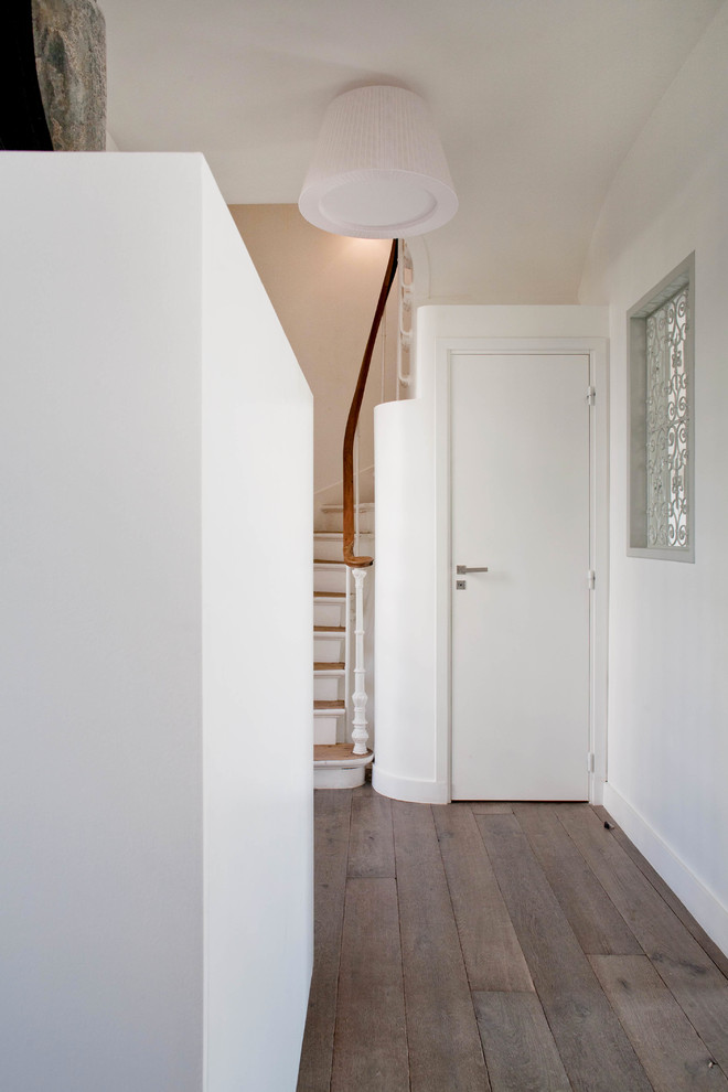 Cette image montre un escalier courbe minimaliste avec des marches en bois et un garde-corps en bois.