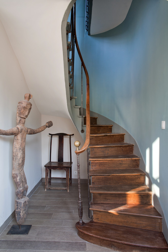 Foto på en stor eklektisk svängd trappa i trä, med sättsteg i trä och räcke i trä