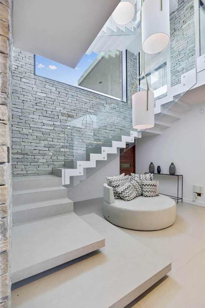 Свежая идея для дизайна: огромная п-образная лестница в современном стиле с ступенями из плитки, подступенками из плитки и стеклянными перилами - отличное фото интерьера