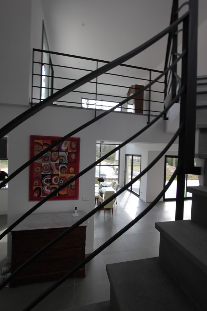 На фото: изогнутая лестница среднего размера в современном стиле с ступенями из известняка, подступенками из известняка и металлическими перилами