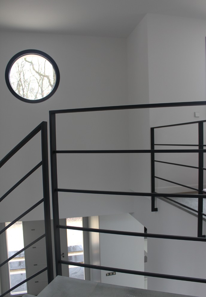 Источник вдохновения для домашнего уюта: большая изогнутая лестница в современном стиле с ступенями из известняка, подступенками из известняка и металлическими перилами