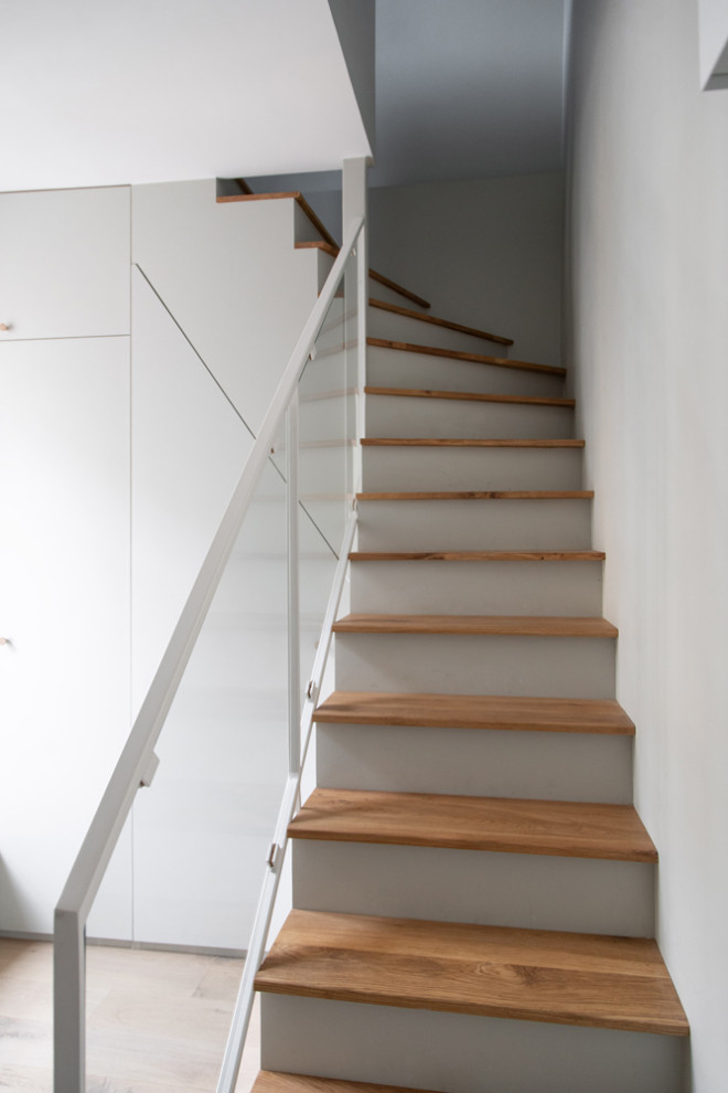 Diseño de escalera curva tradicional pequeña con escalones de madera, contrahuellas de madera pintada y barandilla de varios materiales