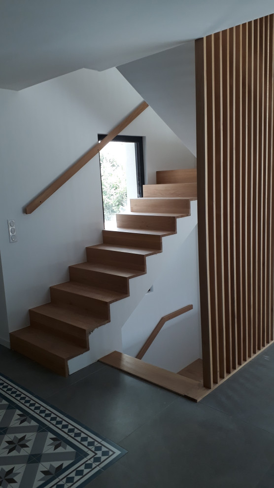 Cette image montre un grand escalier minimaliste en U avec des marches en bois, des contremarches en bois et un garde-corps en bois.
