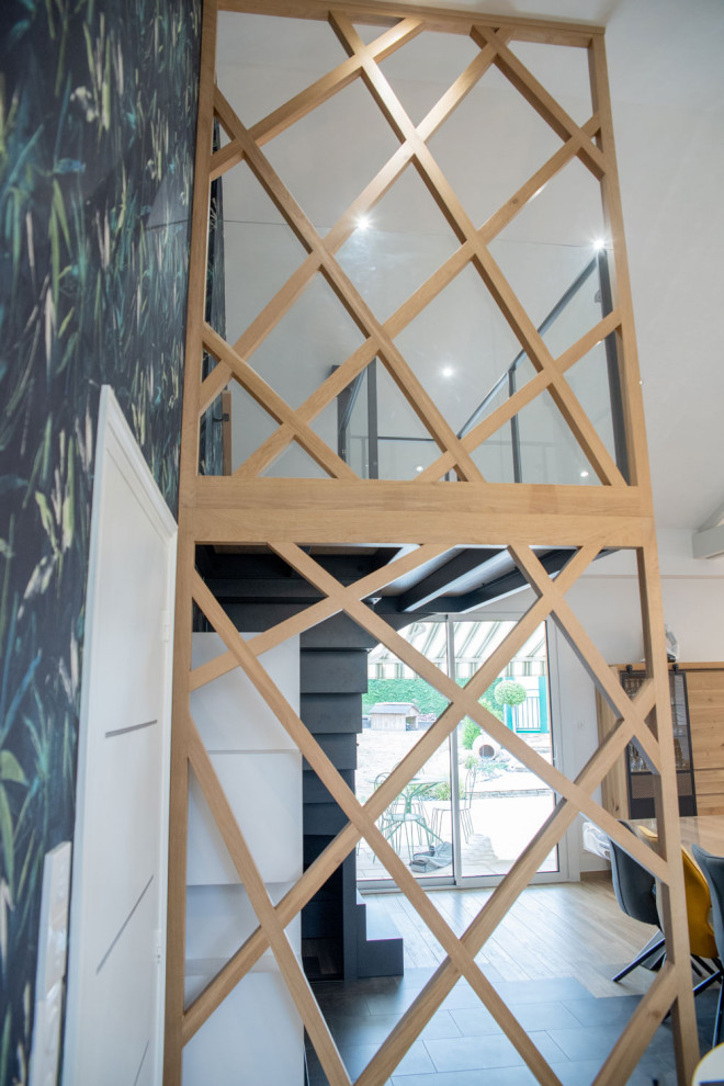 Modelo de escalera en L contemporánea con escalones de metal, contrahuellas de metal, barandilla de vidrio y papel pintado