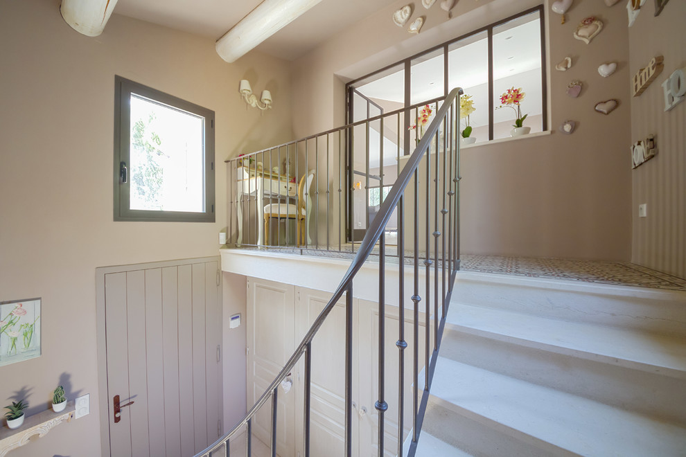 Diseño de escalera en L de estilo de casa de campo de tamaño medio con escalones de piedra caliza, contrahuellas de piedra caliza y barandilla de metal