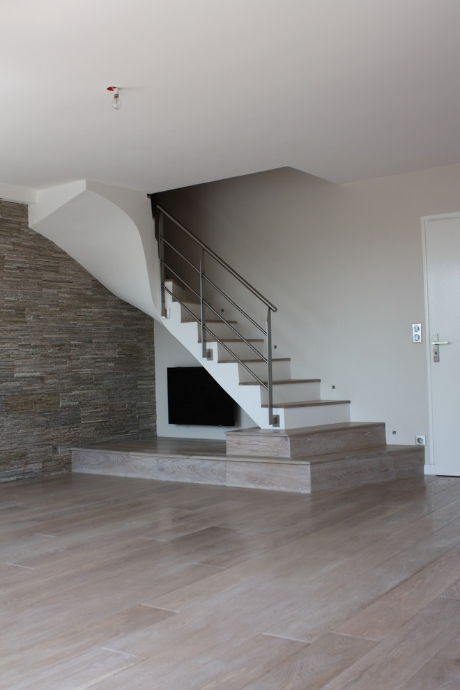 Cette photo montre un escalier peint tendance en U de taille moyenne avec des marches en bois et un garde-corps en métal.