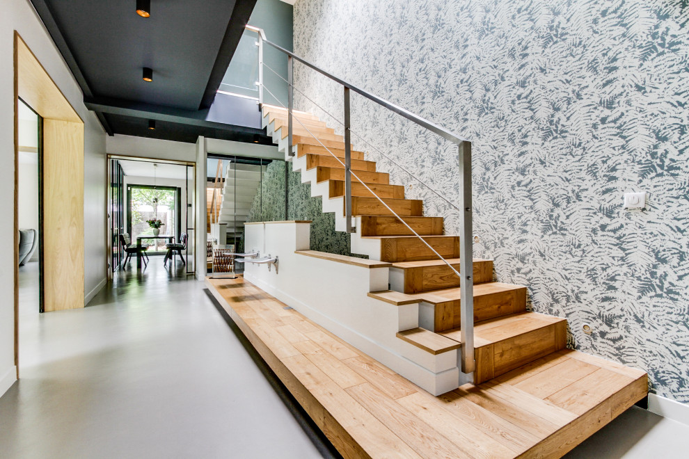 Ejemplo de escalera recta contemporánea grande con escalones de madera, contrahuellas de madera, barandilla de metal y papel pintado