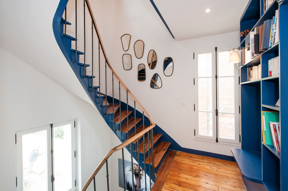 Example of a transitional wooden curved mixed material railing staircase design in Paris with wooden risers