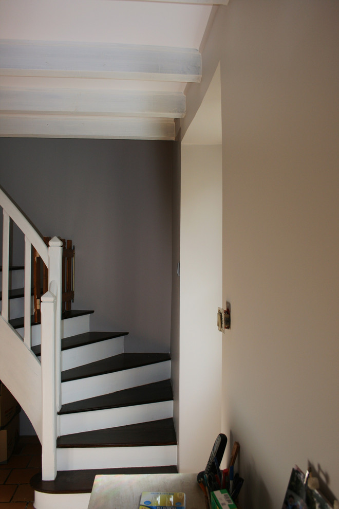Cette photo montre un escalier courbe nature de taille moyenne avec des marches en bois peint, des contremarches en bois et un garde-corps en bois.