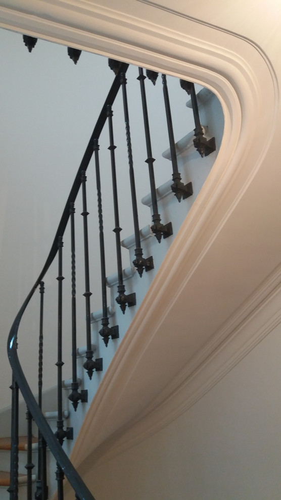 Imagen de escalera de caracol clásica renovada de tamaño medio con escalones de madera, contrahuellas de madera pintada y barandilla de metal