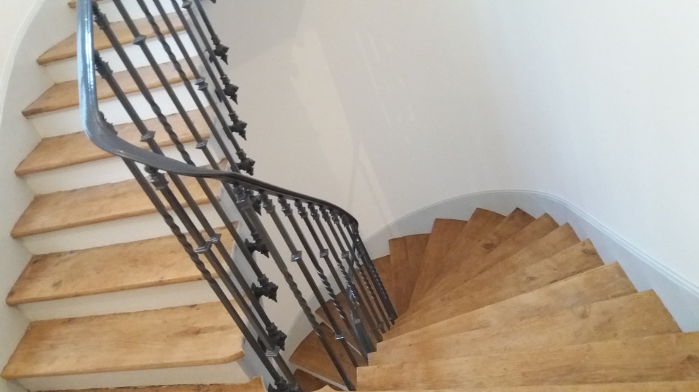На фото: винтовая лестница среднего размера в стиле неоклассика (современная классика) с деревянными ступенями, крашенными деревянными подступенками и металлическими перилами с