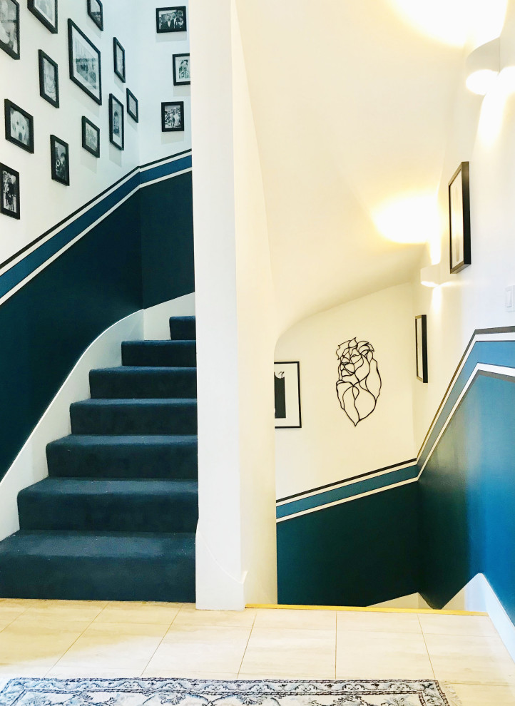 Réalisation d'un grand escalier courbe design avec des marches en moquette, des contremarches en moquette et du papier peint.