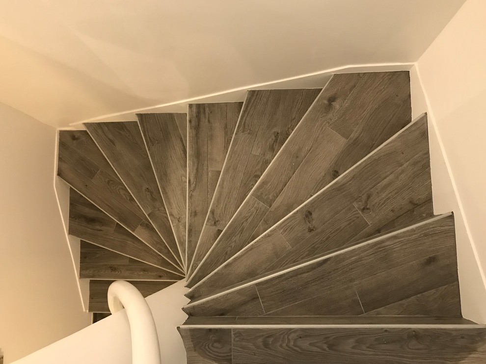 Ejemplo de escalera curva contemporánea de tamaño medio con escalones con baldosas, contrahuellas con baldosas y/o azulejos y barandilla de metal