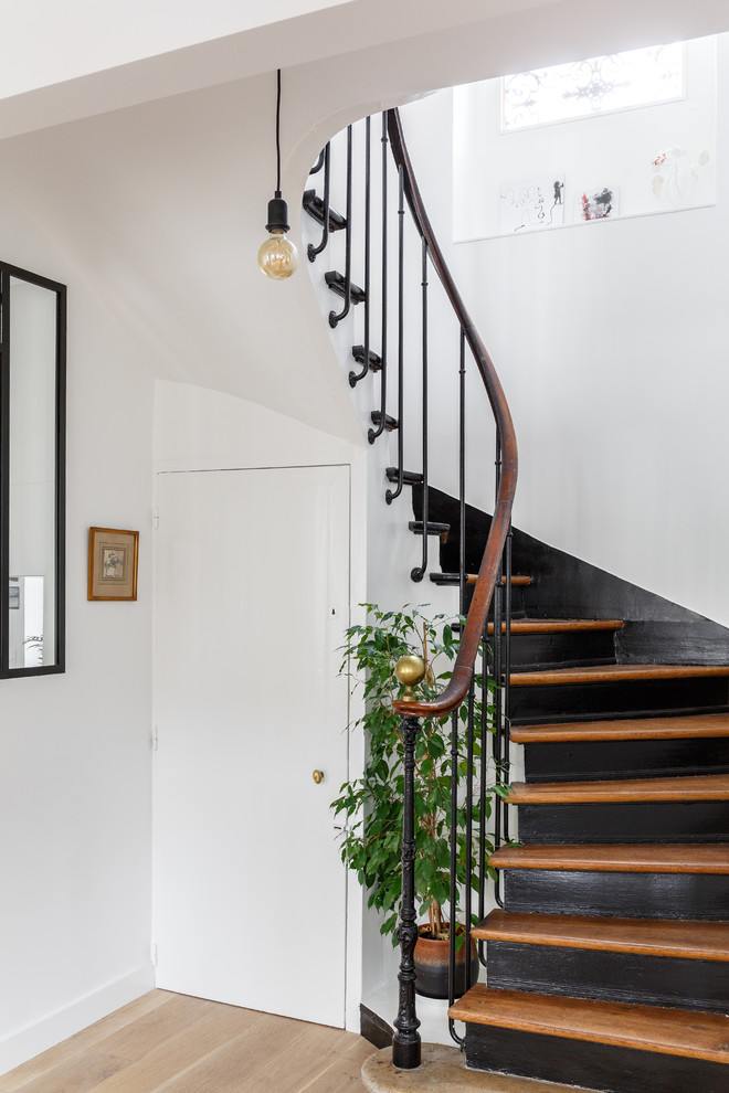 Идея дизайна: изогнутая лестница среднего размера в стиле лофт с деревянными ступенями, крашенными деревянными подступенками и металлическими перилами