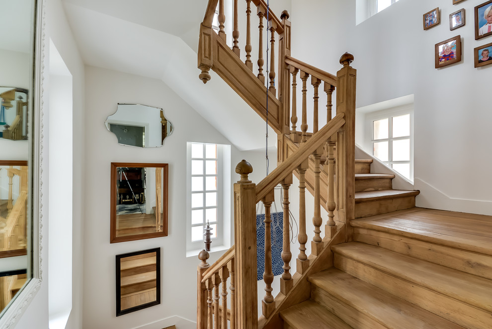 Cette photo montre un grand escalier chic en U avec des marches en bois et des contremarches en bois.